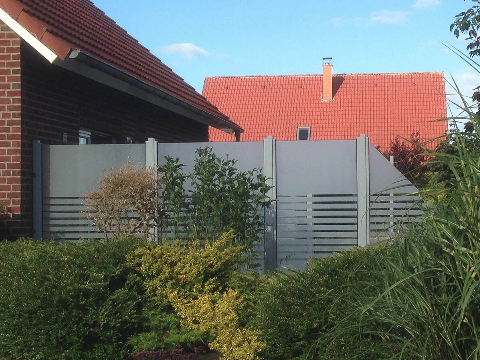 Moderner Aluminium-Sichtschutzzaun in Grau mit teils geschlossenen und teils horizontalen Elementen