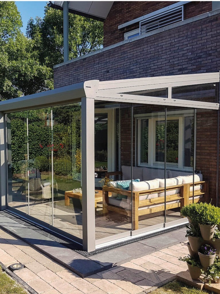 Moderne Terrassenüberdachung aus Aluminium mit rahmenlosen Glasschiebewänden und überdachtem Sitzbereich