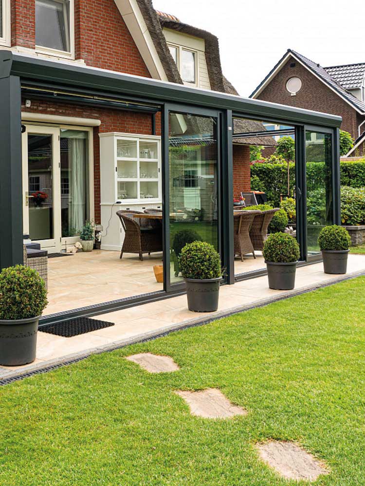 Angebaute Terrassenüberdachung aus Aluminium mit großen Glasschiebewänden
