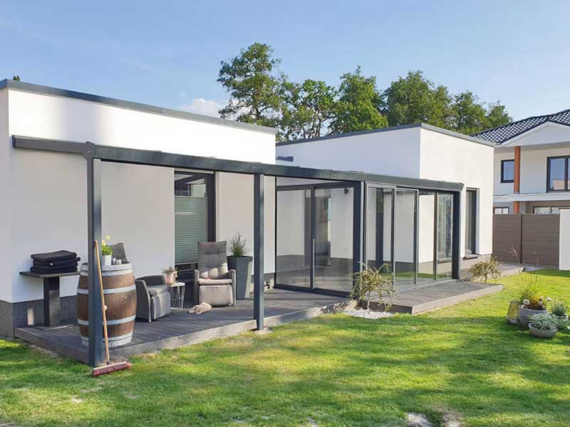 Sommergarten 21 Moderne Aluminium-Terrassenüberdachung mit durchgehenden Glasschiebewänden an einem Bungalow