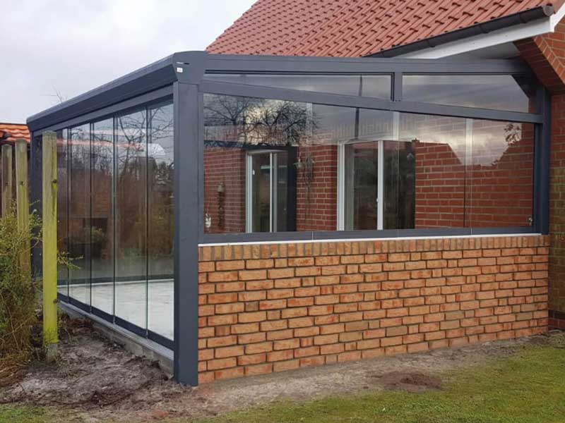 Sommergarten 22 Teilunterkalteter Wintergarten aus Aluminium mit Glasdach und Glasschiebewänden auf Klinkersockel